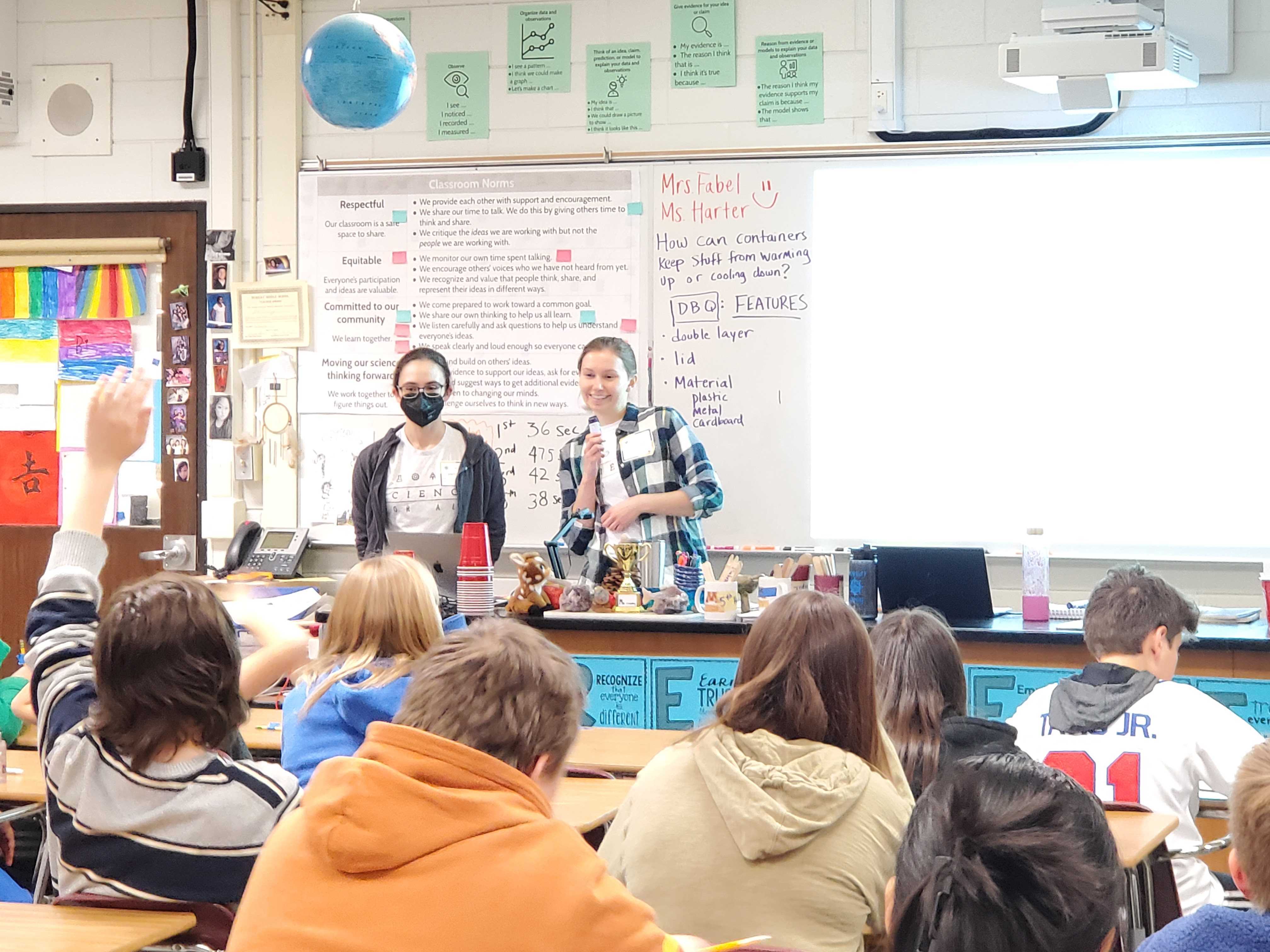 Emily and Kaylie answering a student's question during their presentation at the front of the classroom. 