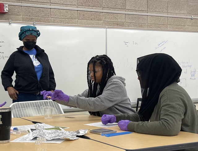 Students spool polymer "rope" out of a glass beaker