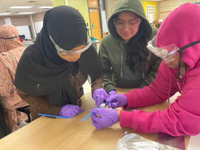 Students smile and work together to spool polymer "rope"
