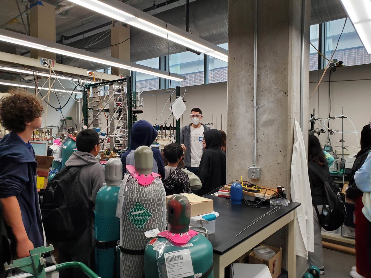 Brian Bayer showcases an instrument in his lab to a group of students. 
