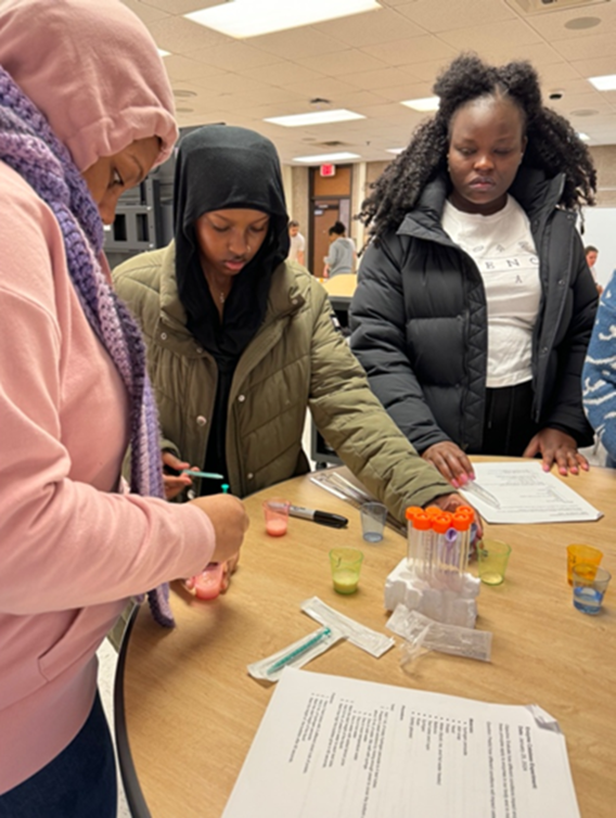 Students and an SFA volunteer prepare colorful yeast solutions in beakers.